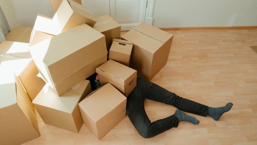 Un homme sous une pile de carton parce qu'il a besoin d'un professionnel pour son déménagement