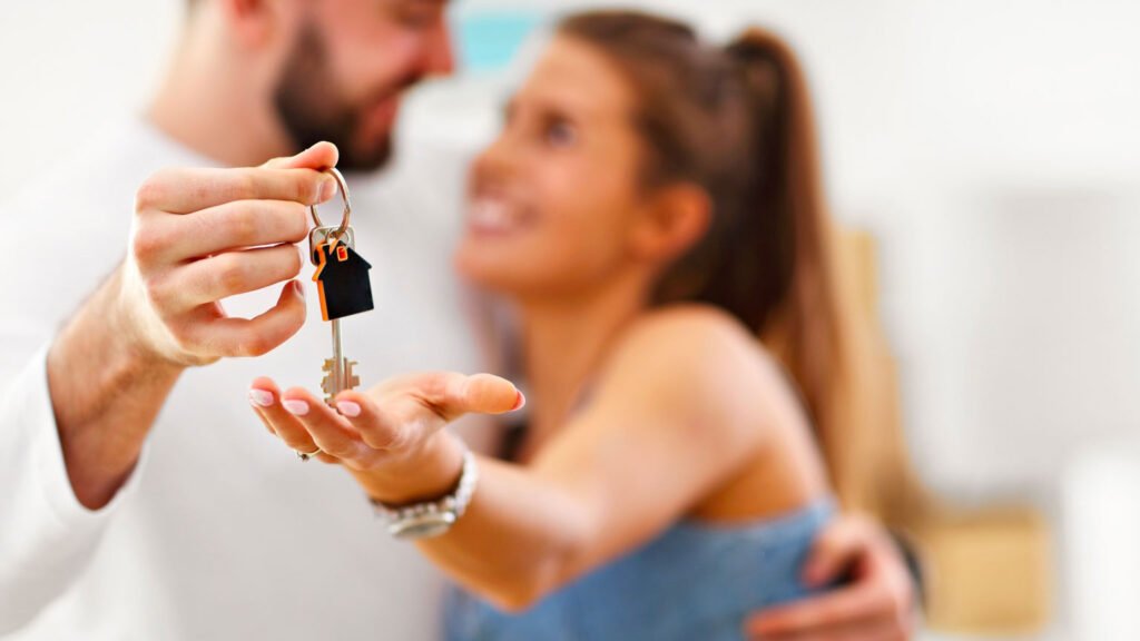 Un couple prêt à déménager à l'aide de professionnel tenant des clés dans la main